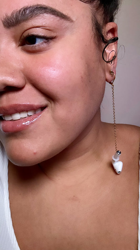 Close-up of a person wearing a unique earring with a Bluetooth attached a gold chain.